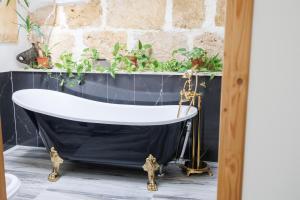 a bathroom with a black and white tub with plants at Ire' Luxury Suite in Avola