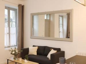 a living room with a black couch and a mirror at Notre Dame de Senlis by La boite en Plus in Senlis