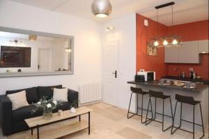a living room with a black couch and a kitchen at Notre Dame de Senlis by La boite en Plus in Senlis