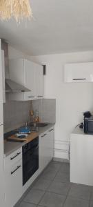 a kitchen with white cabinets and a black stove at Appartement les saladelles in Le Grau-du-Roi