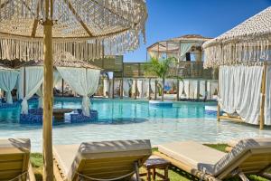 a resort swimming pool with chairs and umbrellas at Alia Beachfront Suites and Spa in Haraki