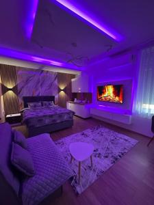 a purple room with a couch and a fireplace at Studio Apartman Kostić in Gracanica