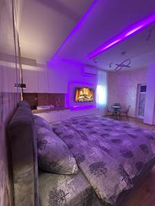 a bedroom with a large bed with purple lighting at Studio Apartman Kostić in Gracanica
