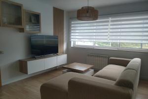 a living room with a couch and a flat screen tv at Apartamento "Playa de Sada" in Sada