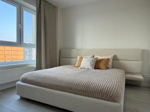 a bed in a white room with a large window at Bird's eye Apartment with sea view 18th floor in Klaipėda