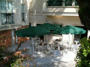 a patio with tables and chairs and green umbrellas at Hotel O Lagar in Cambados