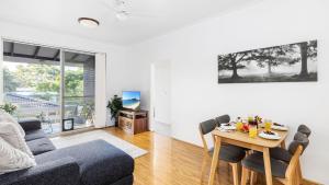 a living room with a couch and a table with chairs at Beachside at Gretel in Nelson Bay