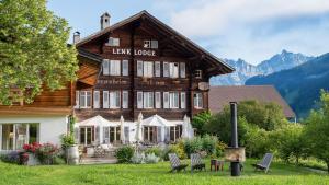 a large wooden house with chairs in front of it at Lenk Lodge - Boutique & Design Hotel und Apartements in Lenk