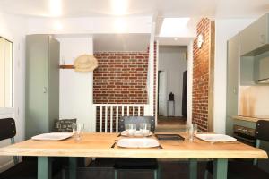 a dining room with a table and a brick wall at Suite Garden by La Boîte En Plus in Senlis