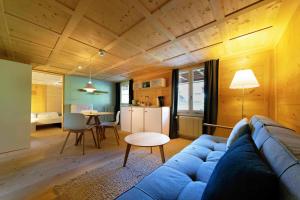 a living room with a blue couch and a kitchen at Lenk Lodge - Boutique & Design Hotel und Apartements in Lenk
