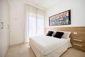 a white bedroom with a white bed and a painting on the wall at Pilone del Monaco - Pool & Free Parking in Vieste
