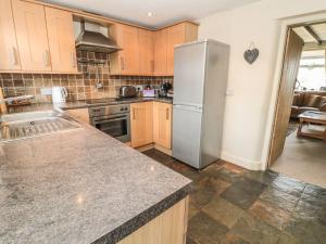 a kitchen with a stainless steel refrigerator and wooden cabinets at Shepherds Nook in Chathill +23 photos