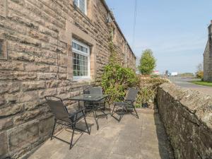 a table and chairs sitting next to a brick wall at Shepherds Nook in Chathill