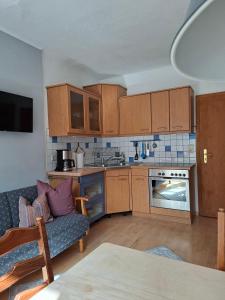 a small kitchen with wooden cabinets and a couch at Ferienwohnungen Schneiderhäusl inkl. Chiemgaukarte in Ruhpolding