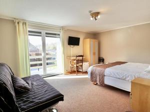 a bedroom with a bed and a couch and a window at Le Petit Vallon in Polleur