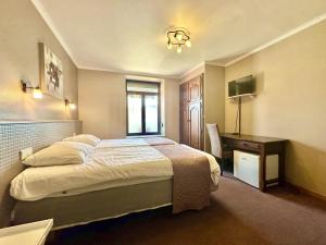 a hotel room with a bed and a desk at Le Grand Vallon in Polleur