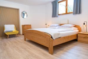 a bedroom with a wooden bed and a yellow chair at Apartments Rožič Bohinj in Bohinj