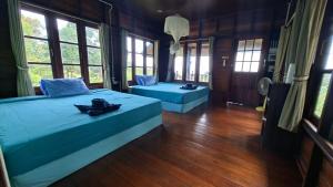 a bedroom with two beds and windows and wooden floors at Koh Phaluay Eco Resort in Ko Phaluai