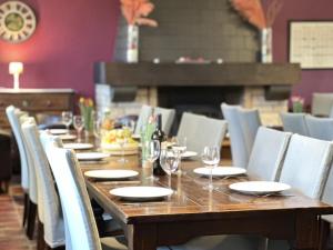 a long wooden table with chairs and wine glasses at Le Petit Vallon in Polleur