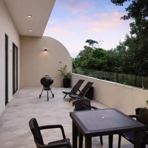 a patio with chairs and tables on a balcony at NEW 2 bed swim-up, gril with jacuzzi Aldea Zamá in Tulum