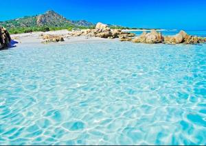 a sandy beach with rocks and the water at Casa relax Berchida in Capo Comino