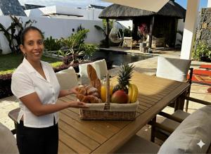 a woman standing in front of a table with a basket of food at Villa Fontainebleau in Grand-Baie