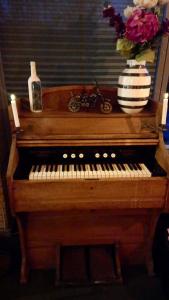 a wooden piano with a vase of flowers and a vase of flowers at Møn Klintholm Vintage B&B in Borre