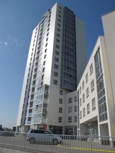 a tall building with a car parked in front of it at Bird's eye Apartment with sea view 18th floor in Klaipėda