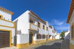 a row of white houses with yellow accents at Casa da Bé in Vila Nova de Milfontes