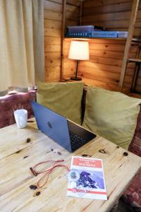 a laptop on a wooden table with a book on it at 1 Bedroom Cabin with Mountain & Loch Views - Quiet Location between Glencoe & Ben Nevis in Onich