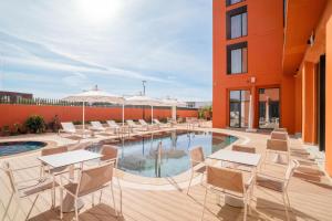 a patio with tables and chairs next to a pool at Hampton By Hilton Ben Guerir in Benguerir