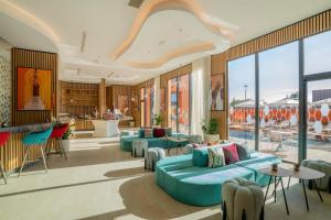 a lobby with blue couches and tables and windows at Hampton By Hilton Ben Guerir in Benguerir