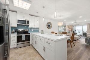 a kitchen with white cabinets and a living room at 2 Bedroom Bayside Condo with Pool in OCMD in Ocean City