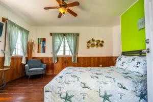a bedroom with a bed with a ceiling fan and a chair at Faro del Colibri in Bocas Town