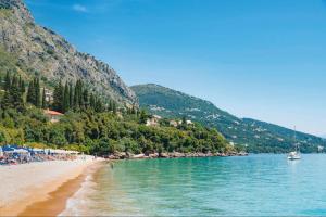 a beach with people and a boat in the water at Hotel Barbati - Seaside Getaways with Pool in Barbati