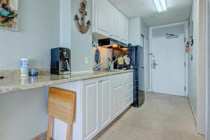 a kitchen with white cabinets and a counter top at The Ocean Calls Harbour Beach 612 in Daytona Beach +12 photos