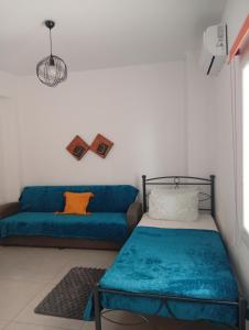 a living room with a couch and a blue bed at Calm Rooms in Agioi Apostoli