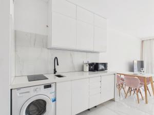 a white kitchen with a washing machine in it at BelMare Seaside Apartment by Solarento in Międzyzdroje