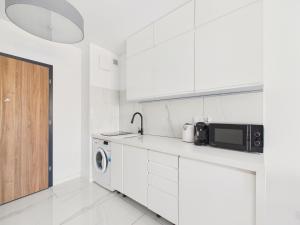 a white kitchen with a sink and a microwave at BelMare Seaside Apartment by Solarento in Międzyzdroje