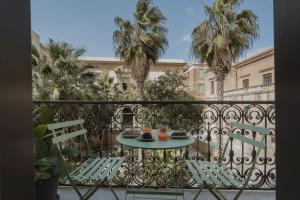 a table and chairs on a balcony with palm trees at Palazzo Lucatelli Suite - Centro in Trapani