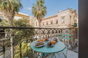 a table with two plates of food on a balcony at Palazzo Lucatelli Suite - Centro in Trapani
