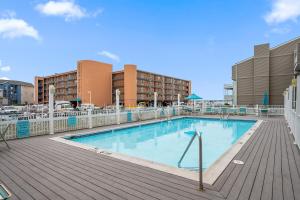 a large swimming pool on a deck with buildings at 2 Bedroom Bayside Condo with Pool in OCMD in Ocean City