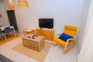 a living room with a yellow chair and a tv at Três Sardinhas in Vila Praia de Âncora