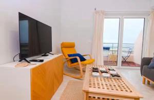 a living room with a tv and a yellow chair at Três Sardinhas in Vila Praia de Âncora