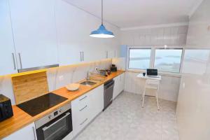 a kitchen with white cabinets and a counter top at Três Sardinhas in Vila Praia de Âncora