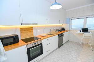 a kitchen with white appliances and a laptop on a table at Três Sardinhas in Vila Praia de Âncora