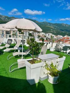 a group of white chairs and tables and an umbrella at Apartments Mitende in Budva