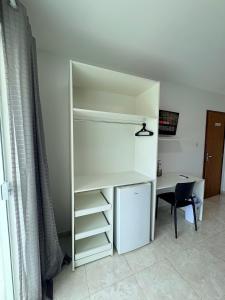 a white book shelf next to a desk and a table at Belaris HOTEL EXECUTIVO - Próximo a Praia do Calhau in São Luís