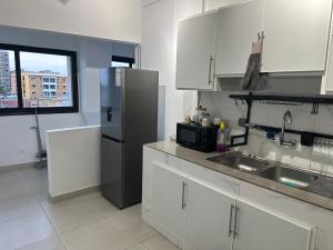 una cucina con mobili bianchi e un frigorifero in acciaio inox di Tranquilité et confort comme à la maison a Abidjan