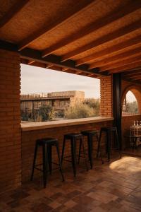 a row of stools on a patio with a brick wall at Hotel Flamora-Valle de Guadalupe in Francisco Zarco
